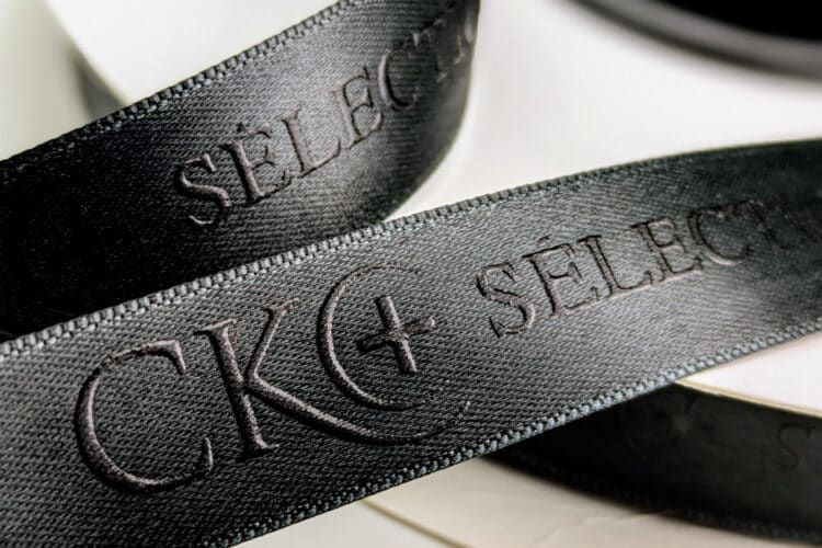 Satinband schwarz mit schwarzem Logodruck als Reliefdruck ausgeführt
